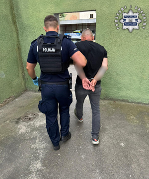 Policjant prowadzi zatrzymanego.