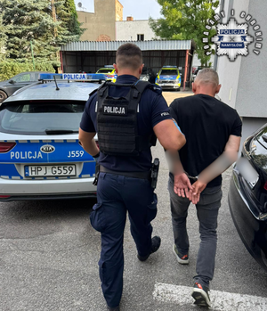 Policjant prowadzi zatrzymanego.