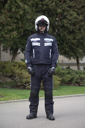 Zdjęcie przedstawia funkcjonariusza Policji w profesjonalnym ubiorze przeznaczonym dla funkcjonariuszy pełniących służbę na motocyklach