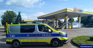 Na pierwszym planie radiowóz policyjny. W głębi stacja benzynowa.