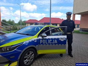 Policjant stoi przy radiowozie.