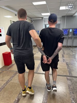 policjant prowadzi zatrzymanego.