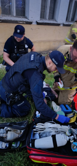 Policjanci podczas udzielania pomocy osobie poszkodowanej w pożarze.