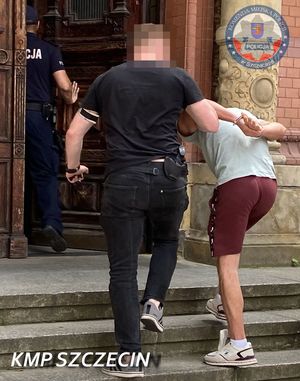 Zatrzymany wprowadzany przez policjanta do budynku.