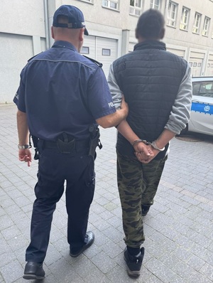 policjant prowadzi zatrzymanego.