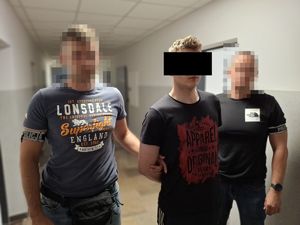 policjanci prowadzą zatrzymanego.