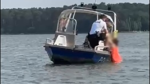 policjanci na łódce wyciągają kobietę.
