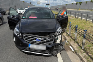 Uszkodzony samochód na drodze ekspresowej z otwartymi drzwiami.
