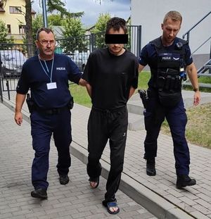 Dwaj funkcjonariusze prowadza zatrzymanego.