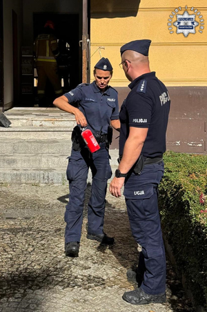 Policjantka trzyma gaśnicę, obok policjant.