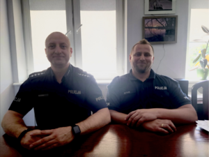 policjanci siedzą przy biurku.