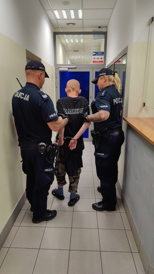 Dwoje policjantów prowadzi zatrzymanego.
