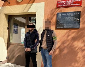 Funkcjonariusz z zatrzymanym w kajdankach.