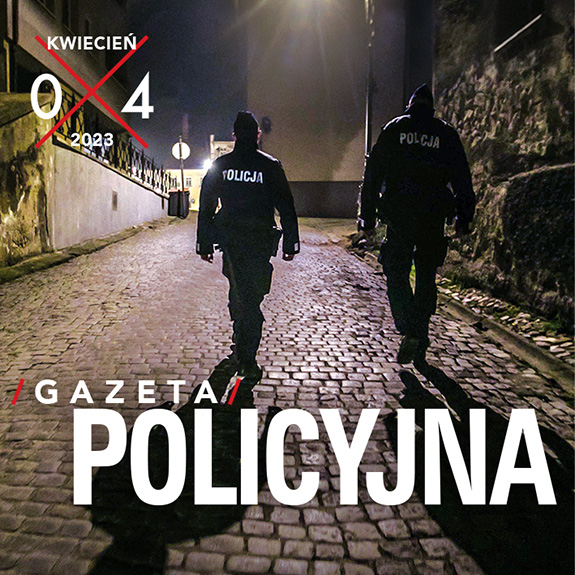 Fragment okładki Gazety Policyjnej przedstawiający dwóch policjantów idących nocą brukowaną ulicą.