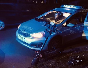 Hulajnoga stoi obok radiowozu policyjnego.