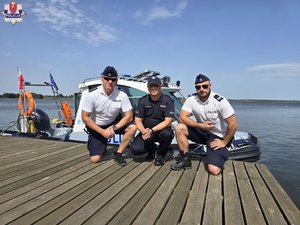 Trzej policjanci na pomoście. Za nimi przycumowana łódź policyjna.