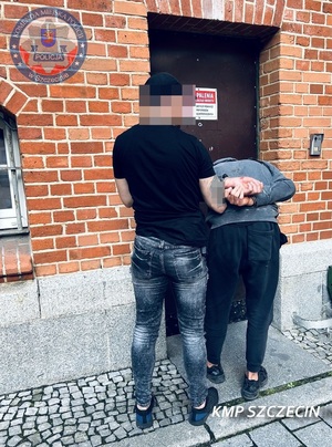 Zatrzymany mężczyzna prowadzony przez policjanta.