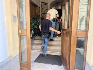 Dwaj policjanci wprowadzają do budynku zatrzymanego mężczyznę.