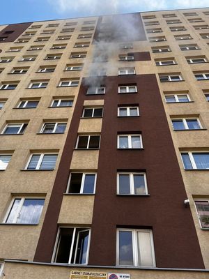Budynek wielopiętrowy, z którego okien wydobywa się dym.
