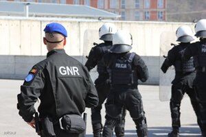 Grupa umundurowanych policjantów w kaskach ochronnych. Na pierwszym planie stoi policjant misji policyjnej w niebieskim berecie