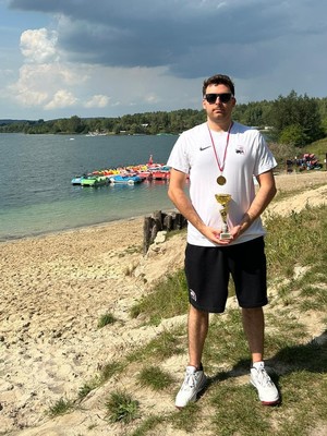 Policjant w sportowym stroju trzyma w ręku trofeum.