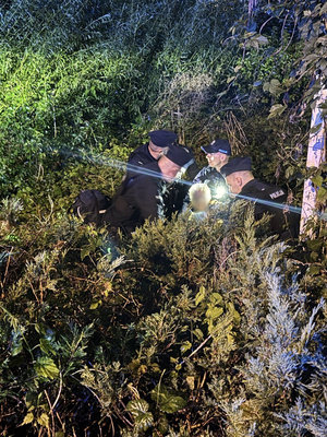 Policjanci z odnaleziona kobietą w zaroślach.