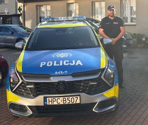 Policjant stoi przy radiowozie.