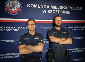 Dwaj umundurowani policjanci stoją z założonymi rękami.