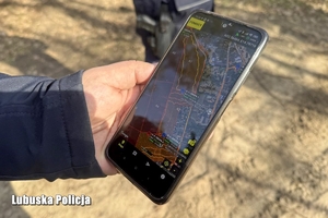 Smartfon trzymany w dłoni. Na ekranie włączona aplikacja z nawigacją.