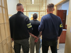 Dwaj policjanci prowadza zatrzymanego.