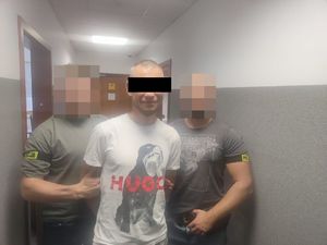 Dwaj policjanci z zatrzymanym na korytarzu.