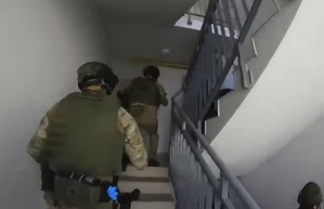 Policjanci na klatce w budynku wchodzą po schodach.