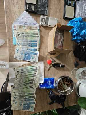 Na blacie leżą rozłożone banknoty, wagi elektroniczne, klucze.