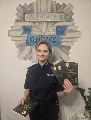 Policjantka  z książeczkami dla dzieci w rękach.
