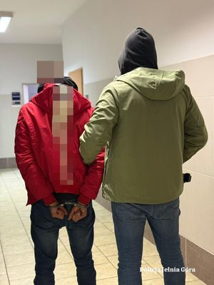 Policjant prowadzi zatrzymanego.
