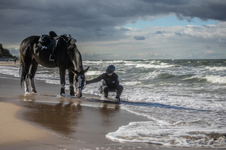 Policjantka z koniem nad brzegiem wody,