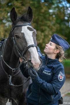 Policjantka trzyma za uzdę swojego konia.