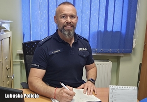 Policjant siedzi  przy biurku.