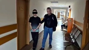 Policjant prowadzi zatrzymanego.