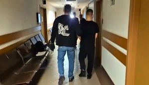 Policjant prowadzi zatrzymanego.