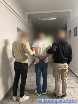 policjanci prowadzą zatrzymanego.