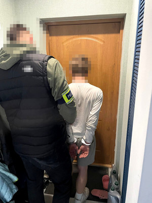 Nieumundurowany policjant wraz z zatrzymanym mężczyzną, który ma założone kajdanki na ręce.