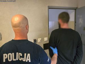 Policjant prowadzi zatrzymanego.