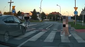 Na zdjęciu przejście dla pieszych. Na lewym pasek widać jadącego na hulajnodze mężczyznę, w którego wjeżdża samochód, na prawym pasie idą dwie osoby.