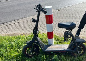 Hulajnoga elektryczna postawiona przy słupku.