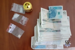Banknoty i narkotyki w woreczkach na stole.