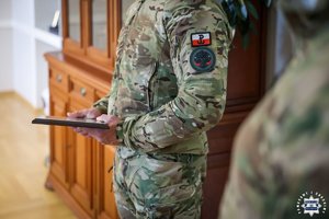 Policjant trzyma w ręku podziękowania.