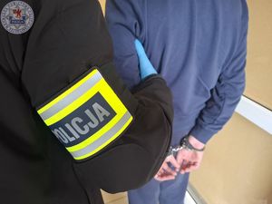 Policjant prowadzi zatrzymanego.