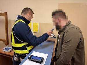 Policjant pobiera odciski palców od mężczyzny.