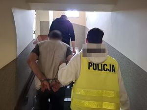 Dwaj policjanci prowadzą zatrzymanego.